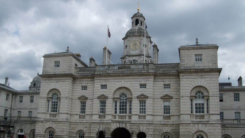 Horse Guards 的浅色长立面围住中央拱道，钟塔从屋顶正中升起。
