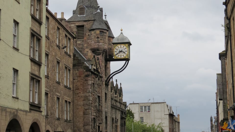 Canongate Tolbooth 的钟楼伸向 Royal Mile 上空，石砌街屋沿坡道向下排列。