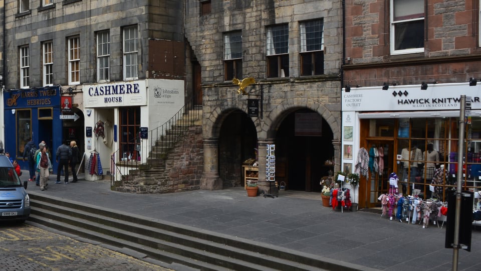 Lawnmarket 的石砌街屋沿 Royal Mile 坡道排列，拱门、台阶和临街铺面构成 Old Town 街景。