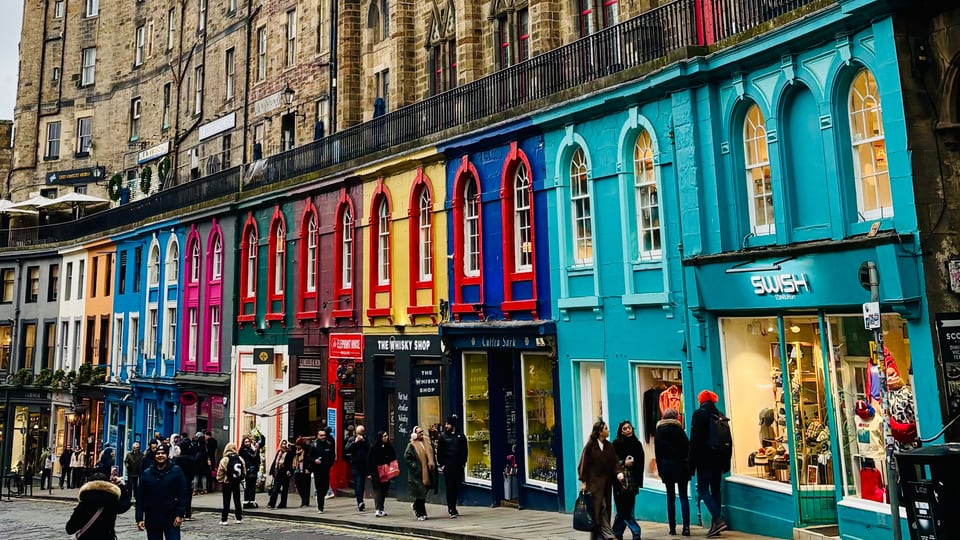 Victoria Street 弯曲下行，彩色店面排在深色石砌建筑下方。
