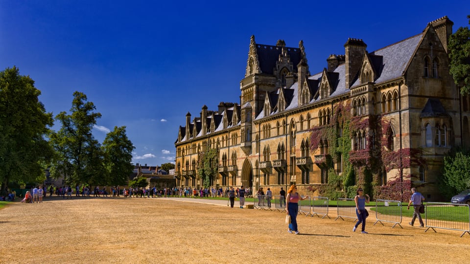 Broad Walk 旁的 Christ Church Meadow Building 沿草地展开，哥特式山墙与秋色藤蔓覆盖长立面。