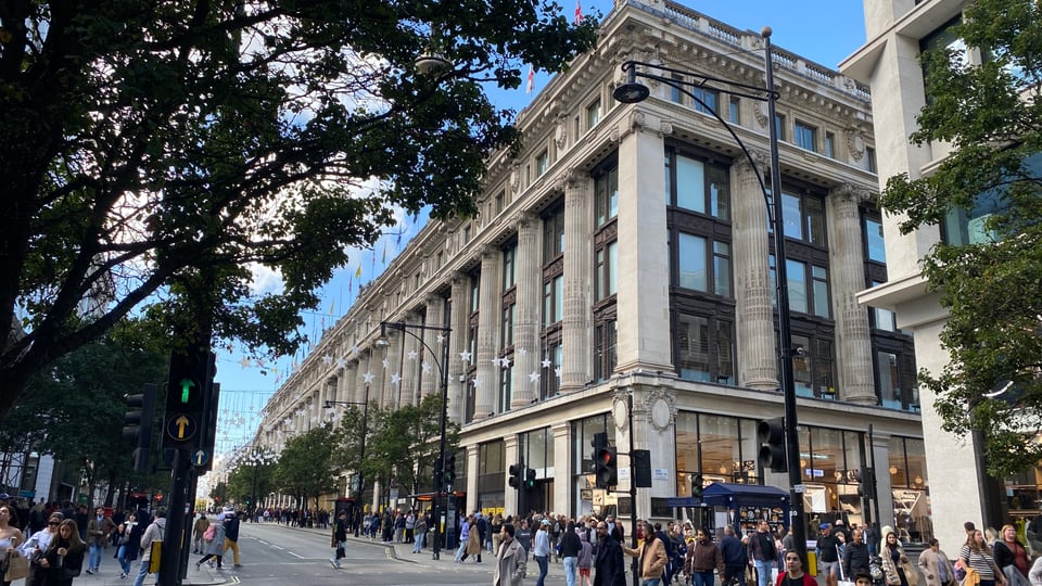 Selfridges London 的 Oxford Street 石材外立面沿街展开，转角柱列与临街橱窗清晰可见。