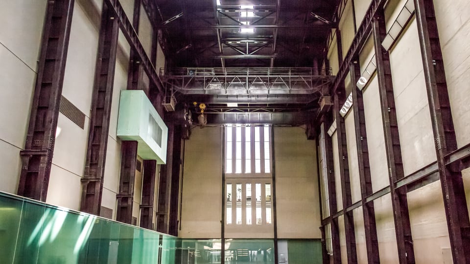 Tate Modern 的 Turbine Hall 以高耸钢架、混凝土墙面和长坡道构成开阔工业空间。